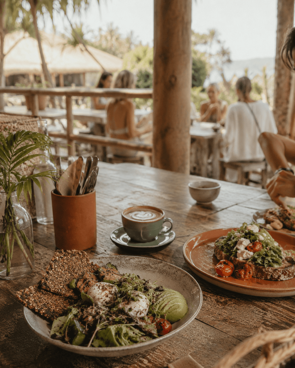 Plates of fresh whole food on a wooden table by the beach
